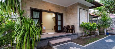 A house with a stone exterior, a front porch with a bench, and a door leading to a room.