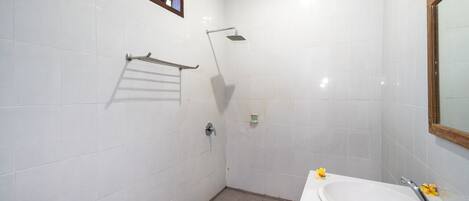 Un baño con ducha, lavamanos y toallero.