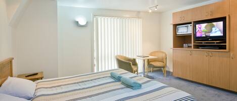 Een hotelkamer met een bed, een televisie, een stoel en een bureau.