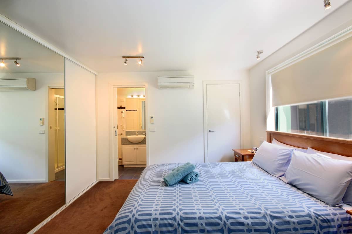 A hotel room with a large bed, a bathroom with a sink and mirror, and a walk-in closet.