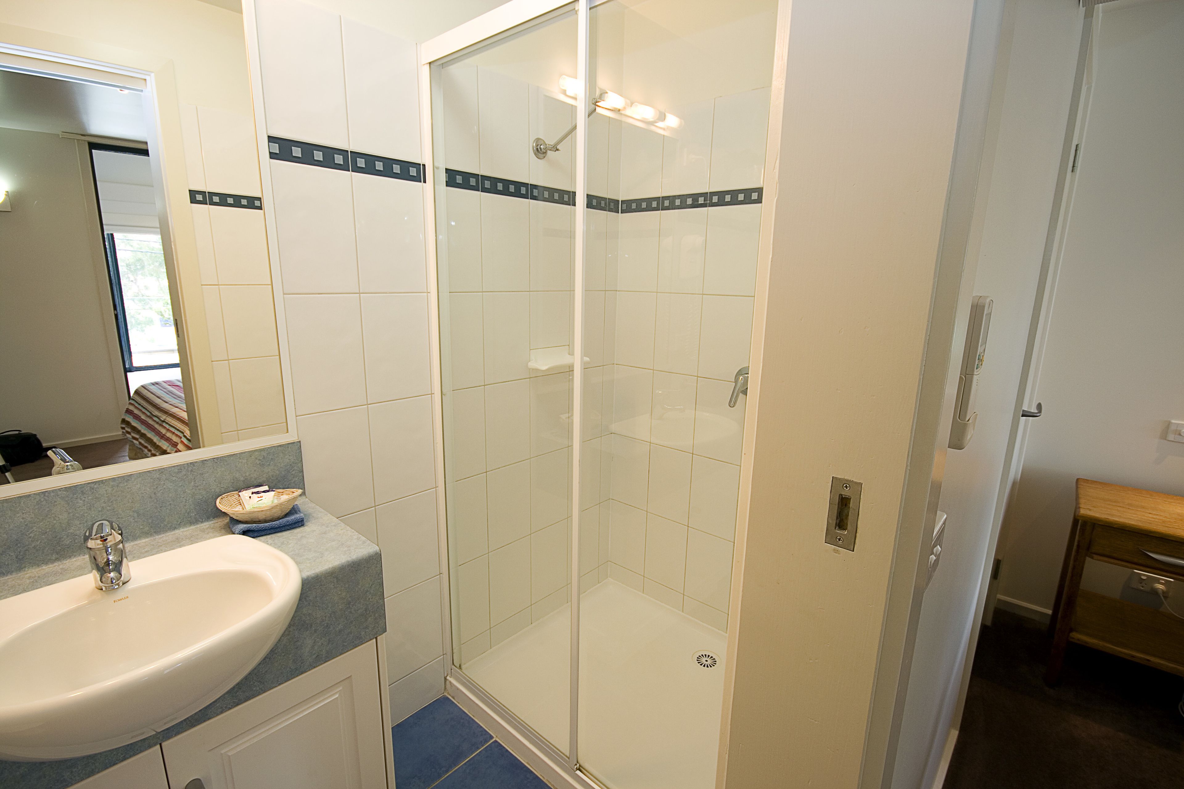 A bathroom with a sink, mirror, and shower.