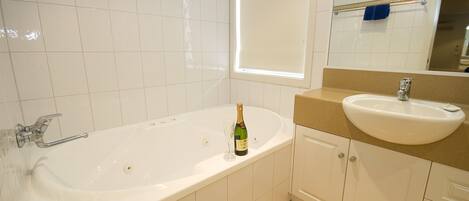 A bathroom with a bathtub, a sink, and a mirror.