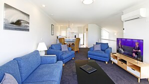 A modern living room with two blue sofas, a coffee table, and a flat-screen TV. - Anchorage Motel and Villas (Lorne)