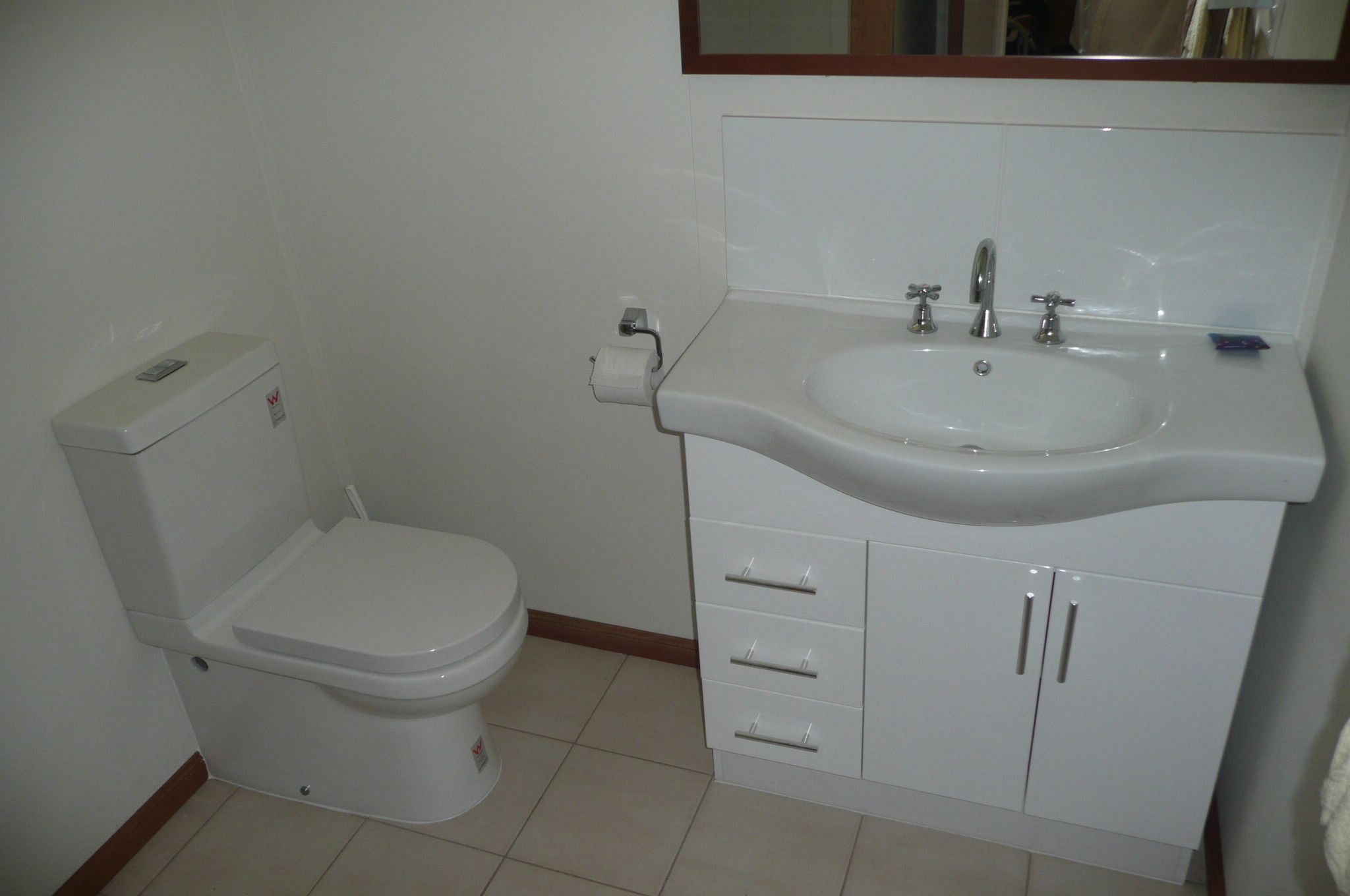 A bathroom with a toilet, sink, and cabinet.