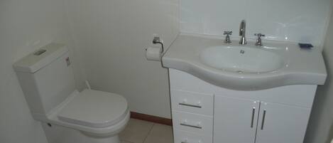 A bathroom with a toilet, sink, and cabinet.