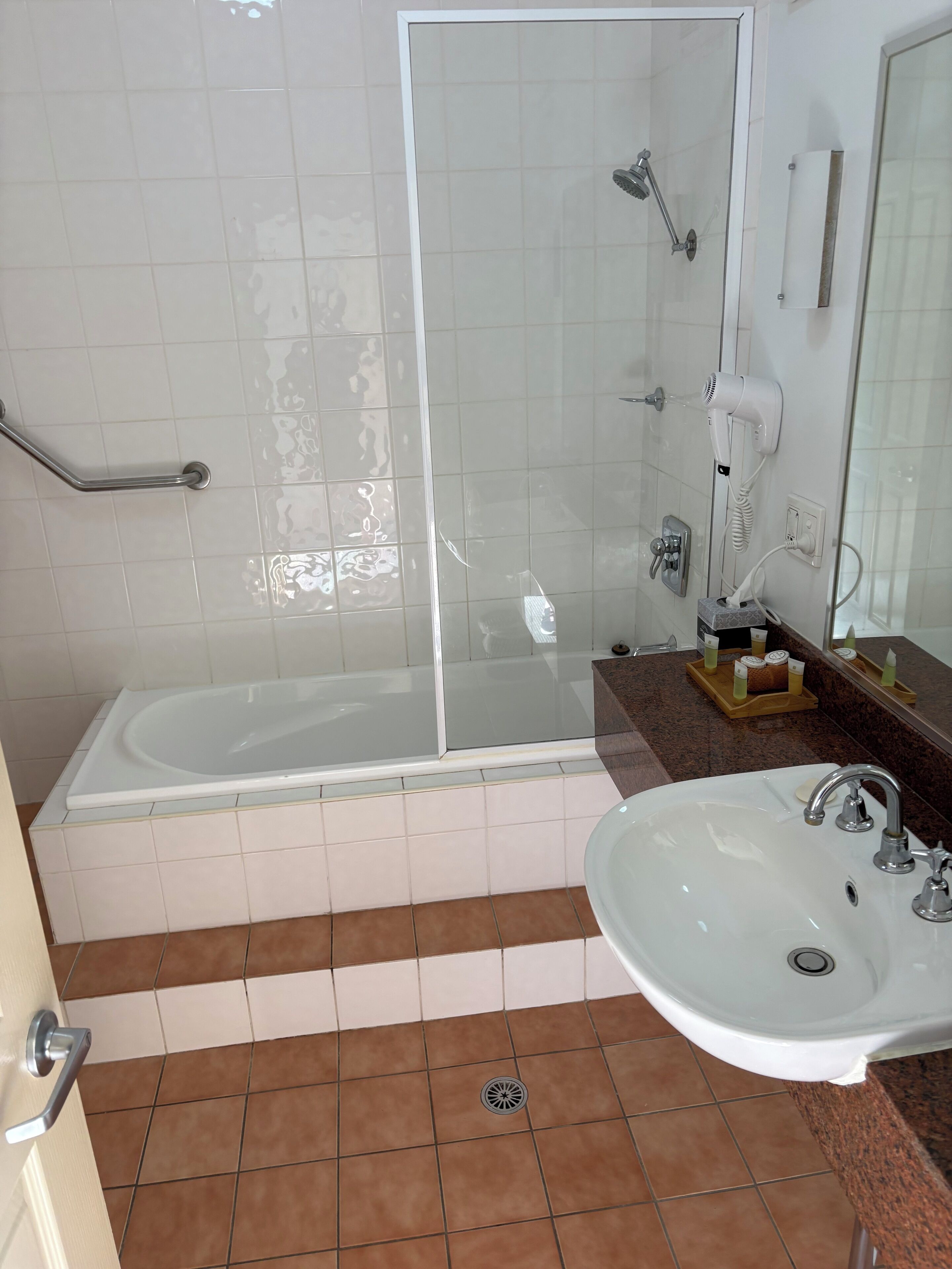 A bathroom with a glass-enclosed shower, a bathtub, a sink, and a vanity with a mirror.