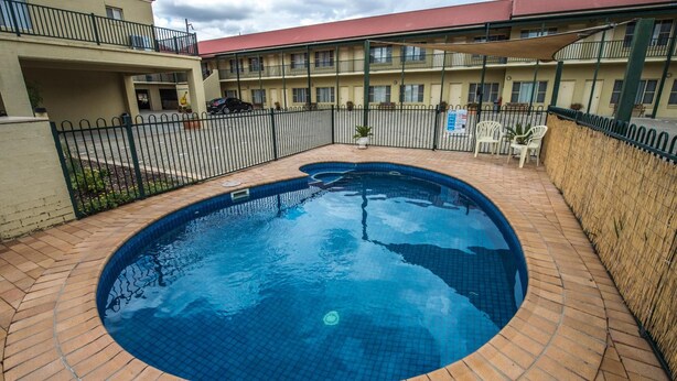 A swimming pool with a tiled edge, surrounded by a brick patio. - Golden Guitar Motor Inn (Hillvue)