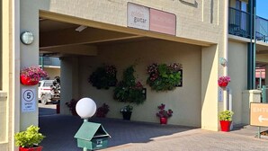 A hotel entrance with a reception sign, a speed limit sign, and potted plants. - Golden Guitar Motor Inn (Hillvue)