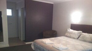 A hotel room with a bed, a chair, and a nightstand. - Christies Beach Hotel (Christies Beach)