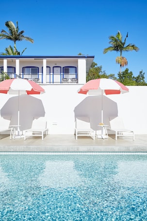 Una piscina al aire libre, sillones reclinables de piscina
