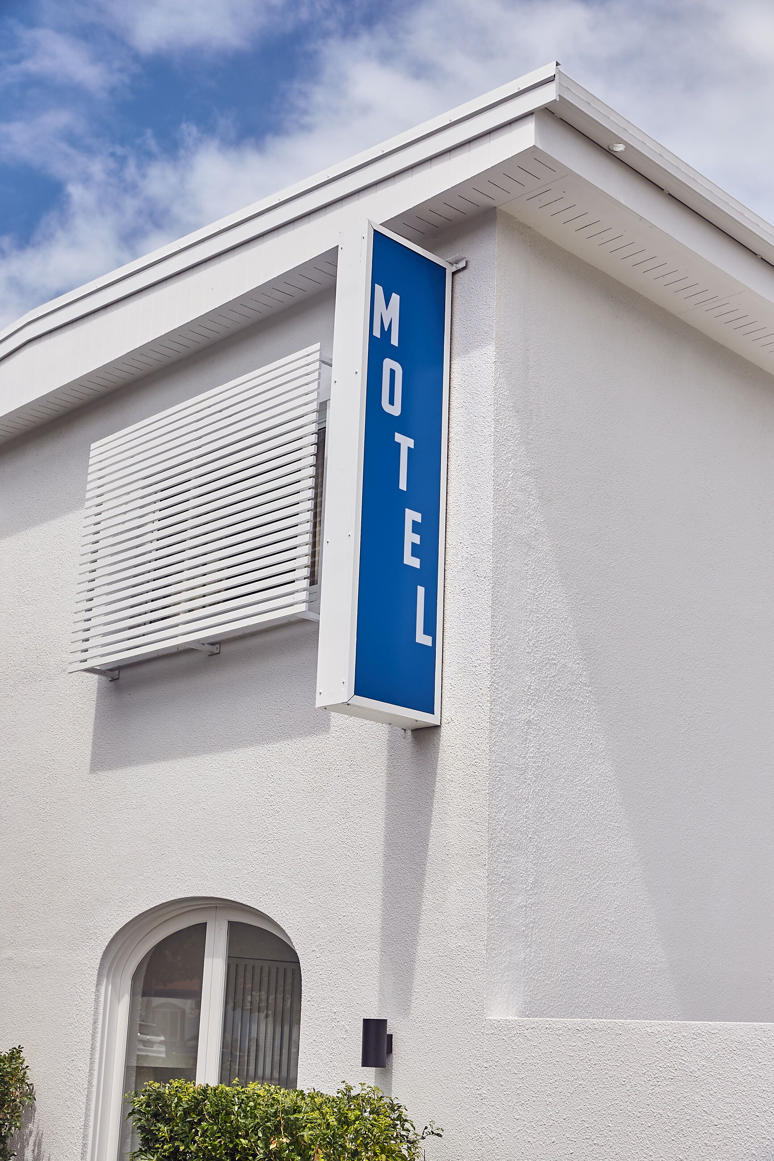 Een motelbord op een wit gebouw met een raam en een deur.