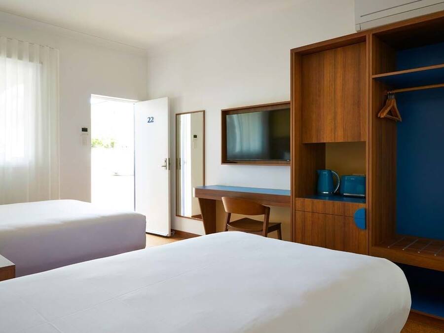 Una habitación de hotel con dos camas, un escritorio, un televisor y un armario.