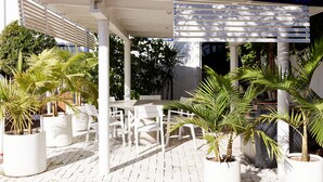 An outdoor patio with white furniture and potted plants. - The Sails Motel Brunswick Heads (Brunswick Heads)