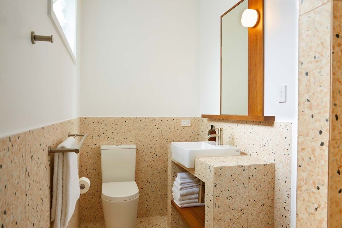 A bathroom with a toilet, sink, and mirror.