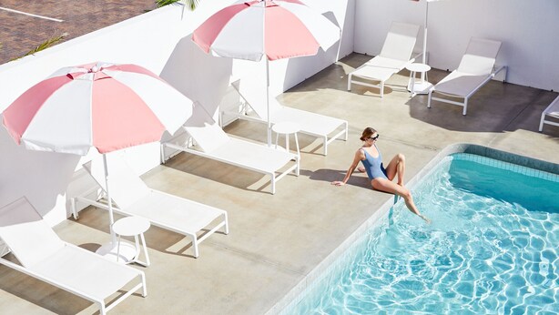A poolside area with lounge chairs and umbrellas. - The Sails Motel Brunswick Heads (Brunswick Heads)