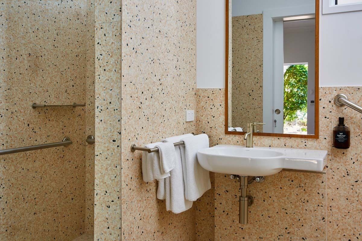 Un baño con lavamanos, espejo, toallero y zona de ducha.
