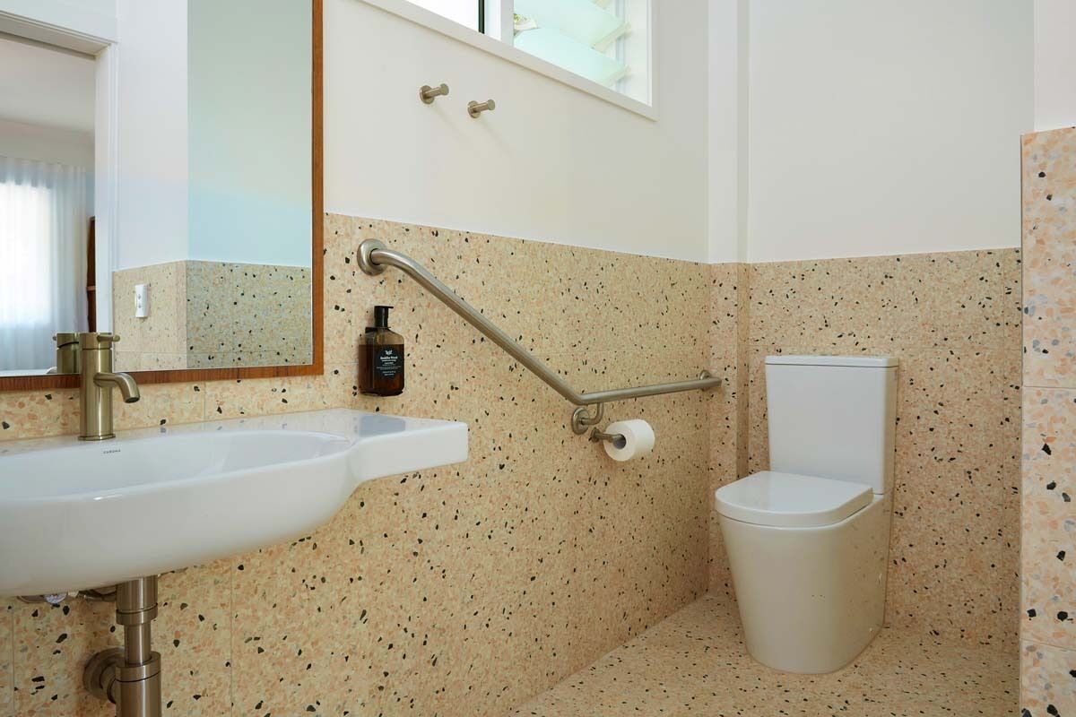 A bathroom with a white sink, a toilet, and a handrail.