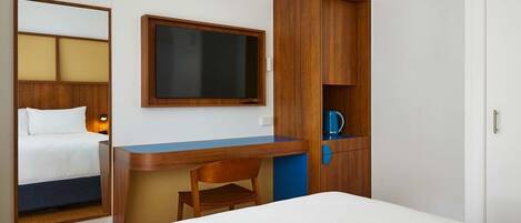 Een hotelkamer met een bed, bureau, stoel, kast en televisie.