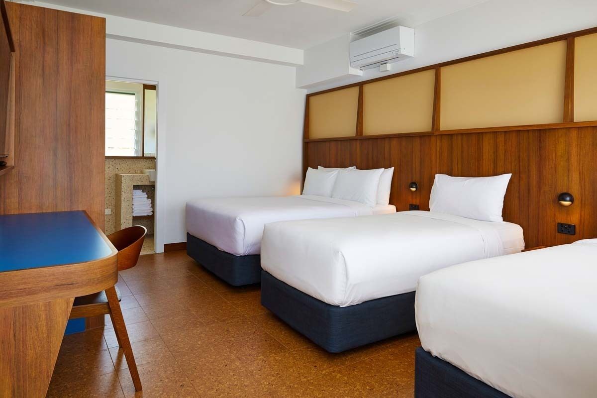 A hotel room with two beds, a wooden headboard, a desk, and a chair.
