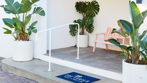 An entrance with a white archway, potted plants, a bench, and a doormat with text. - The Sails Motel Brunswick Heads (Brunswick Heads)