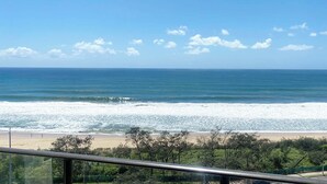 A beach view from a balcony with a railing, ocean waves, and a clear sky. - Meridian Alex Beach Apartments (Alexandra Headland)
