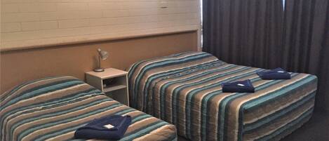 Ett hotellrum med två sängar, ett nattduksbord, en lampa och en tavla på väggen.