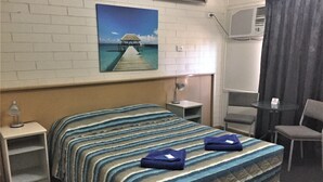 A hotel room with a bed, a desk, a chair, a small table, and a painting of a pier. - Ceduna Motor Inn (Ceduna)