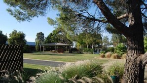 A residential area with a house, a covered outdoor area, and a large tree. - Sportslander Motor Inn (Moama)