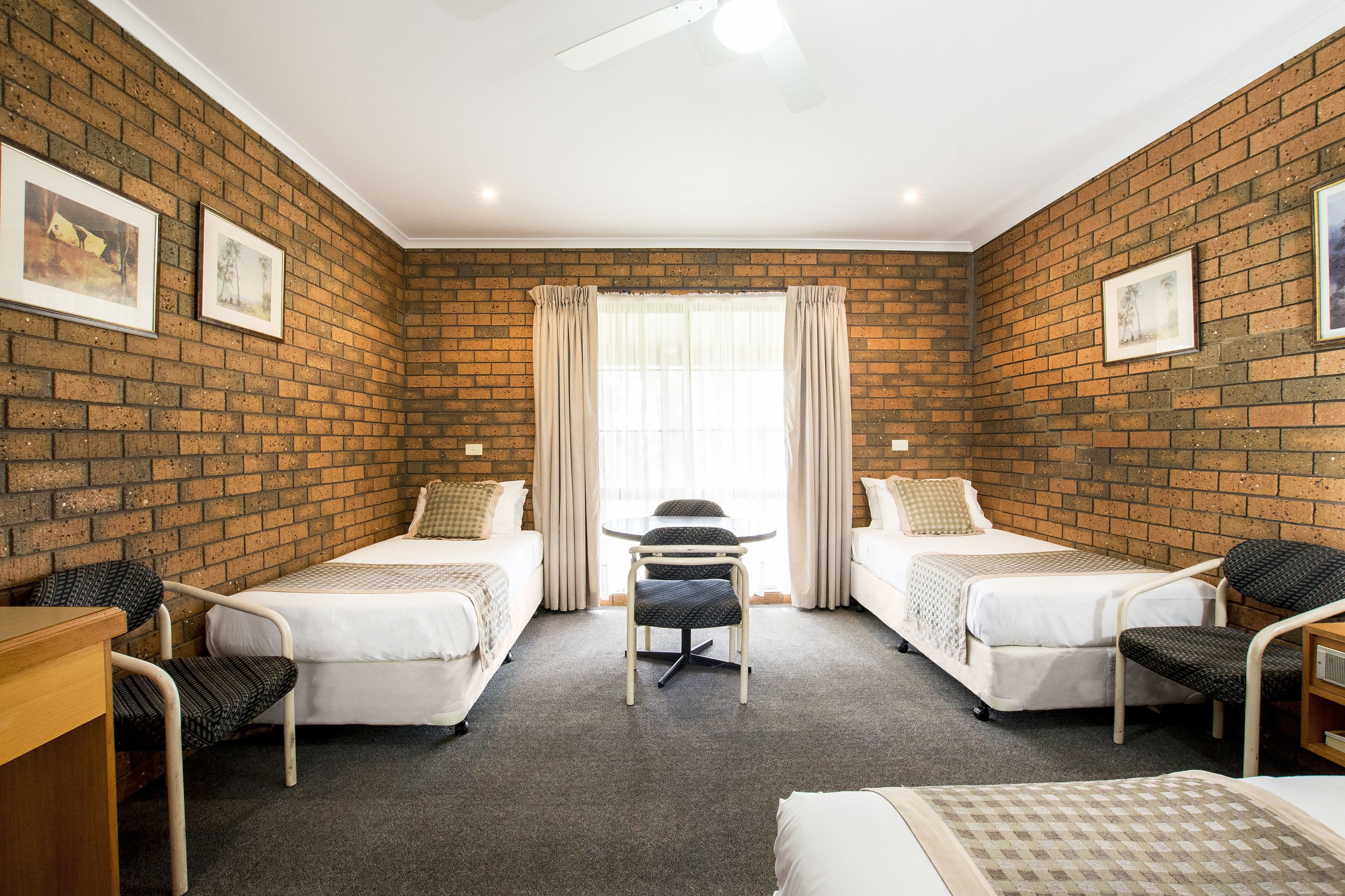 Une chambre d’hôtel avec deux lits simples, une petite table et des chaises.