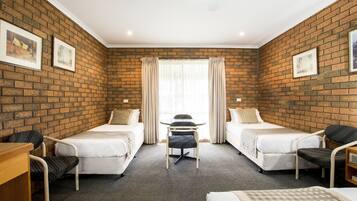 Une chambre d’hôtel avec deux lits simples, une petite table et des chaises.