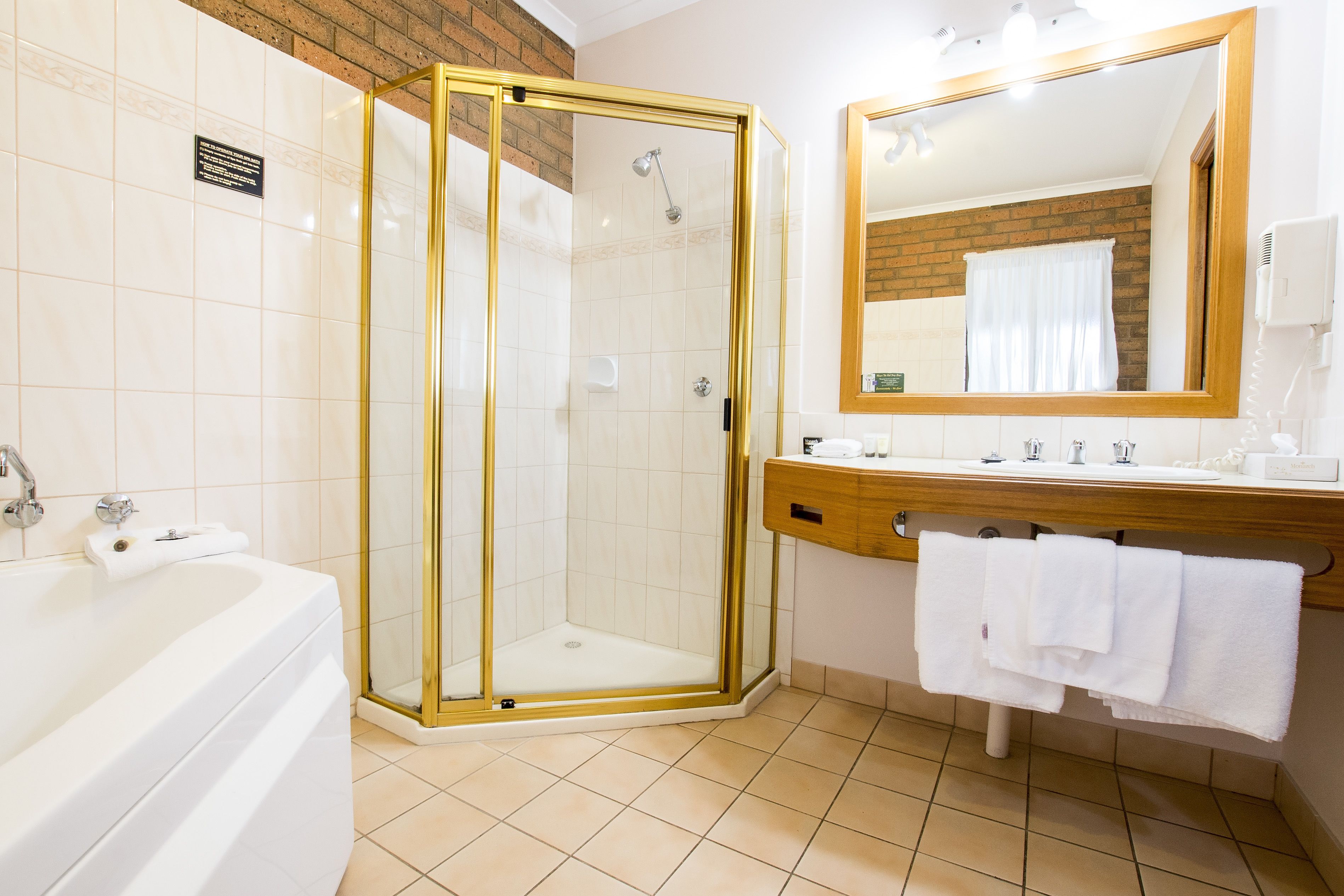 A modern bathroom with a glass-enclosed shower, a white bathtub, and a wooden vanity with a mirror.