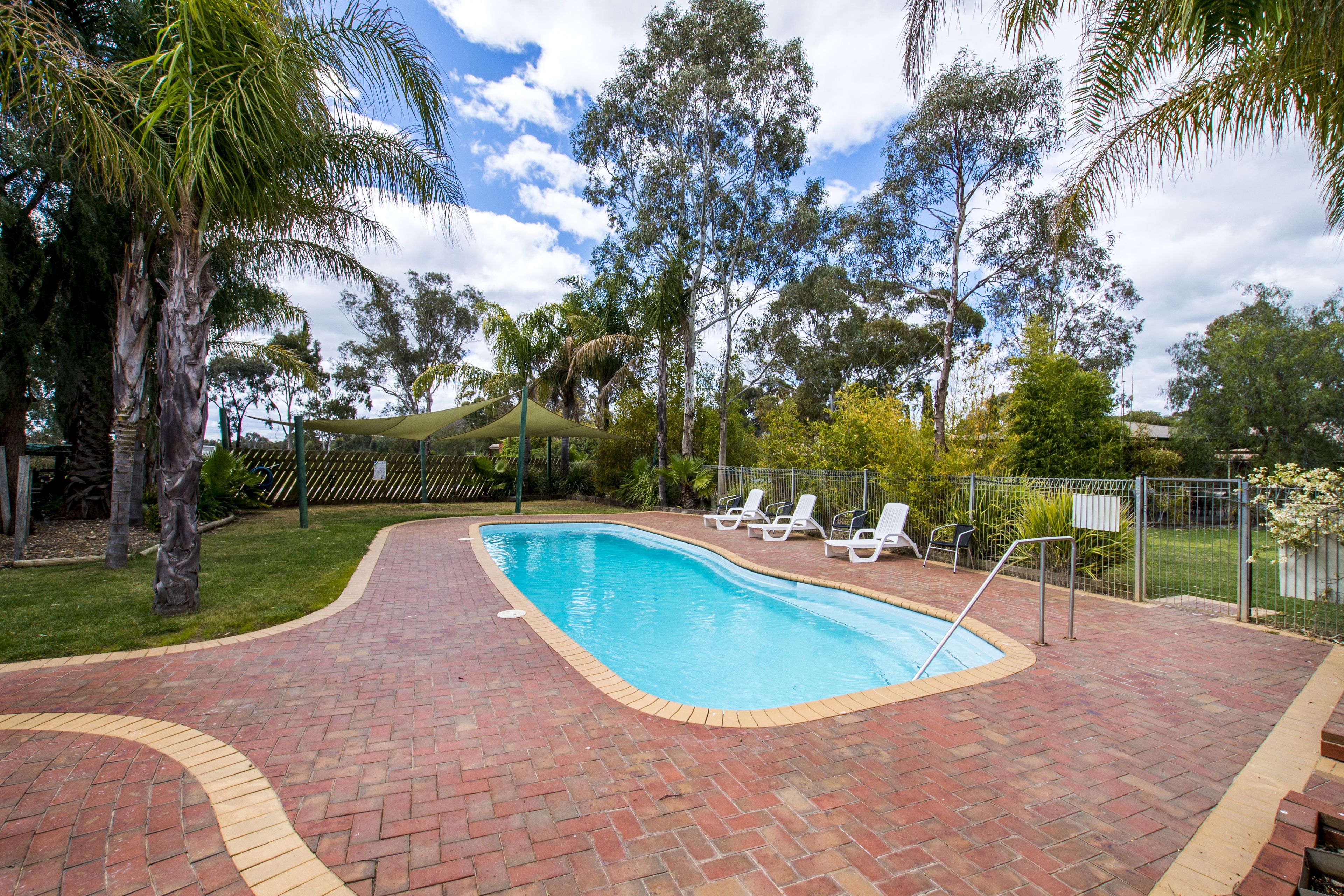 A rectangular swimming pool with a brick border, surrounded by a brick patio.