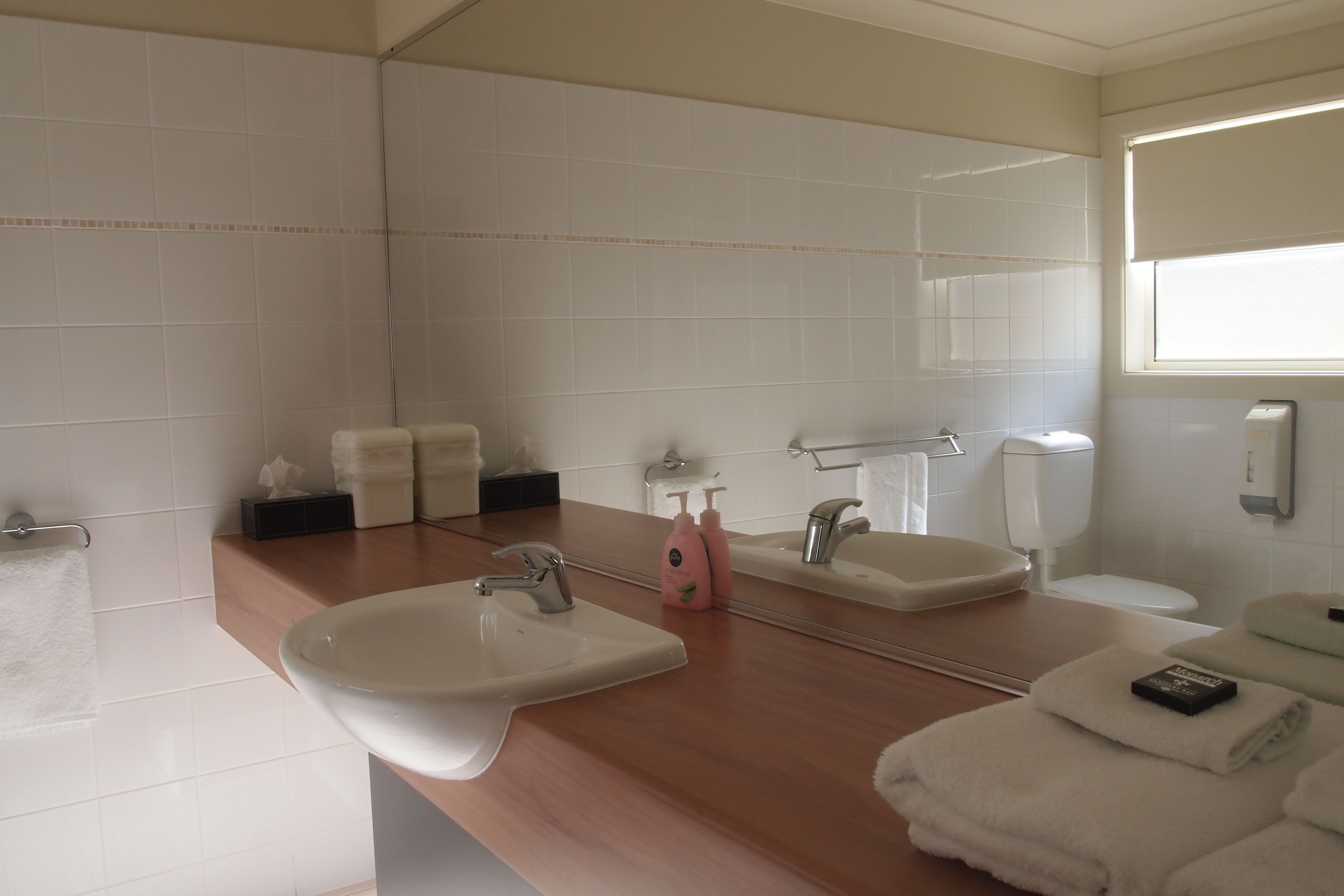 A bathroom with two sinks, a mirror, and a window.
