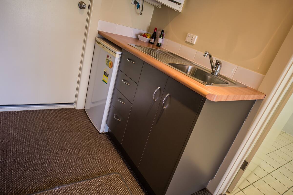 Una cocina compacta con pileta integrada, un refrigerador pequeño y un microondas.