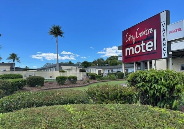 A City Centre motel with a large sign, surrounded by well-maintained landscaping and palm trees. - City Centre Motel (Kempsey)