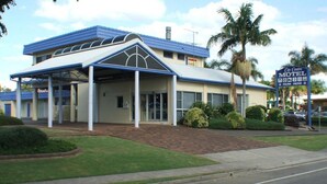 A motel with a covered entrance, palm trees, and a sign indicating a City Centre Motel. - City Centre Motel (Kempsey)