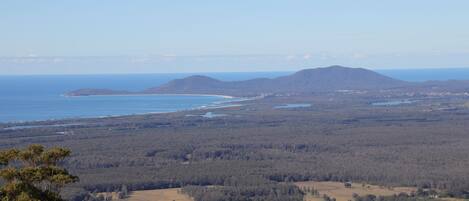A coastal landscape with a view of the sea, hills, and forested areas.