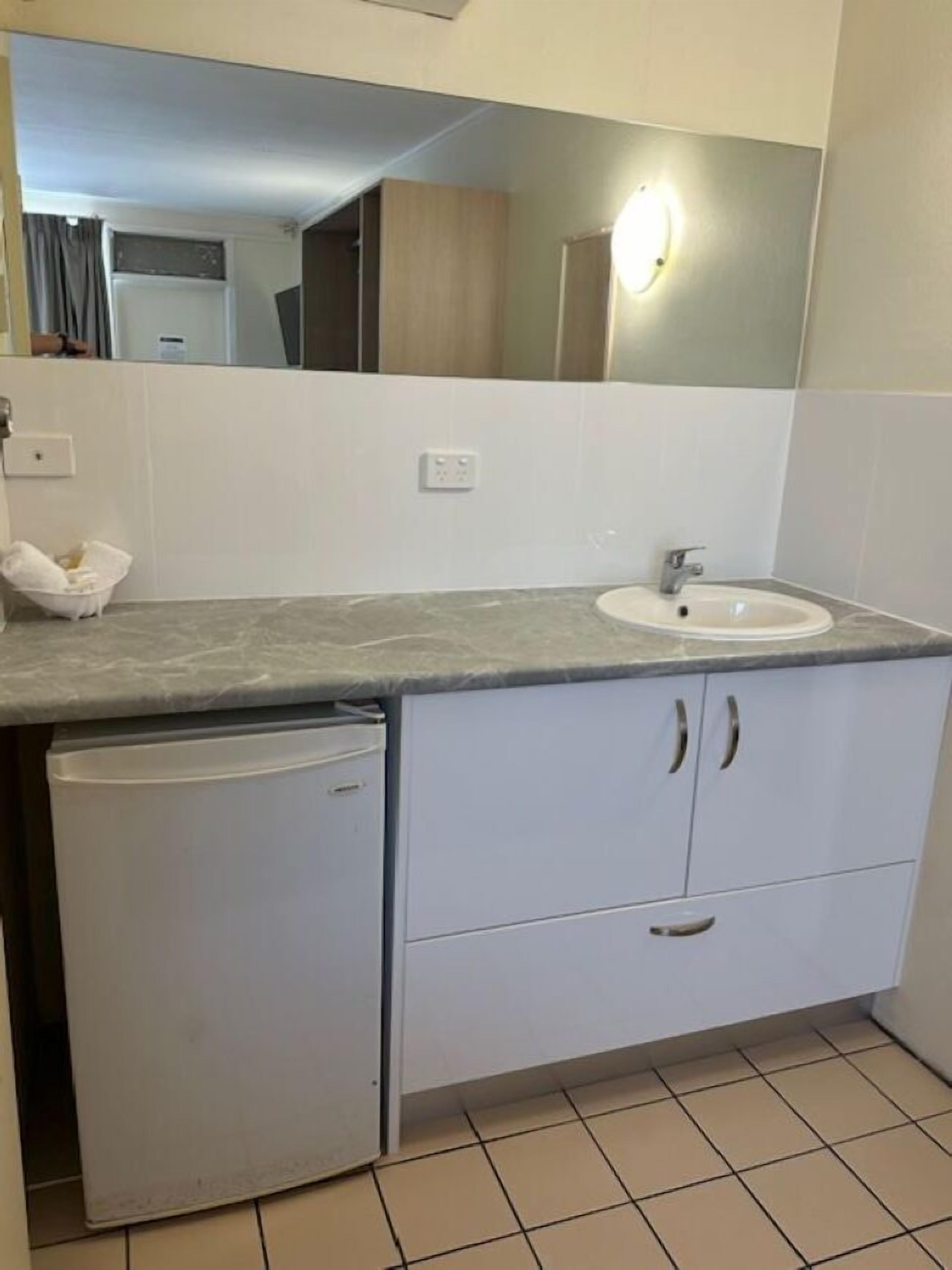 A compact bathroom with a white sink, a mirror, and a small white cabinet.