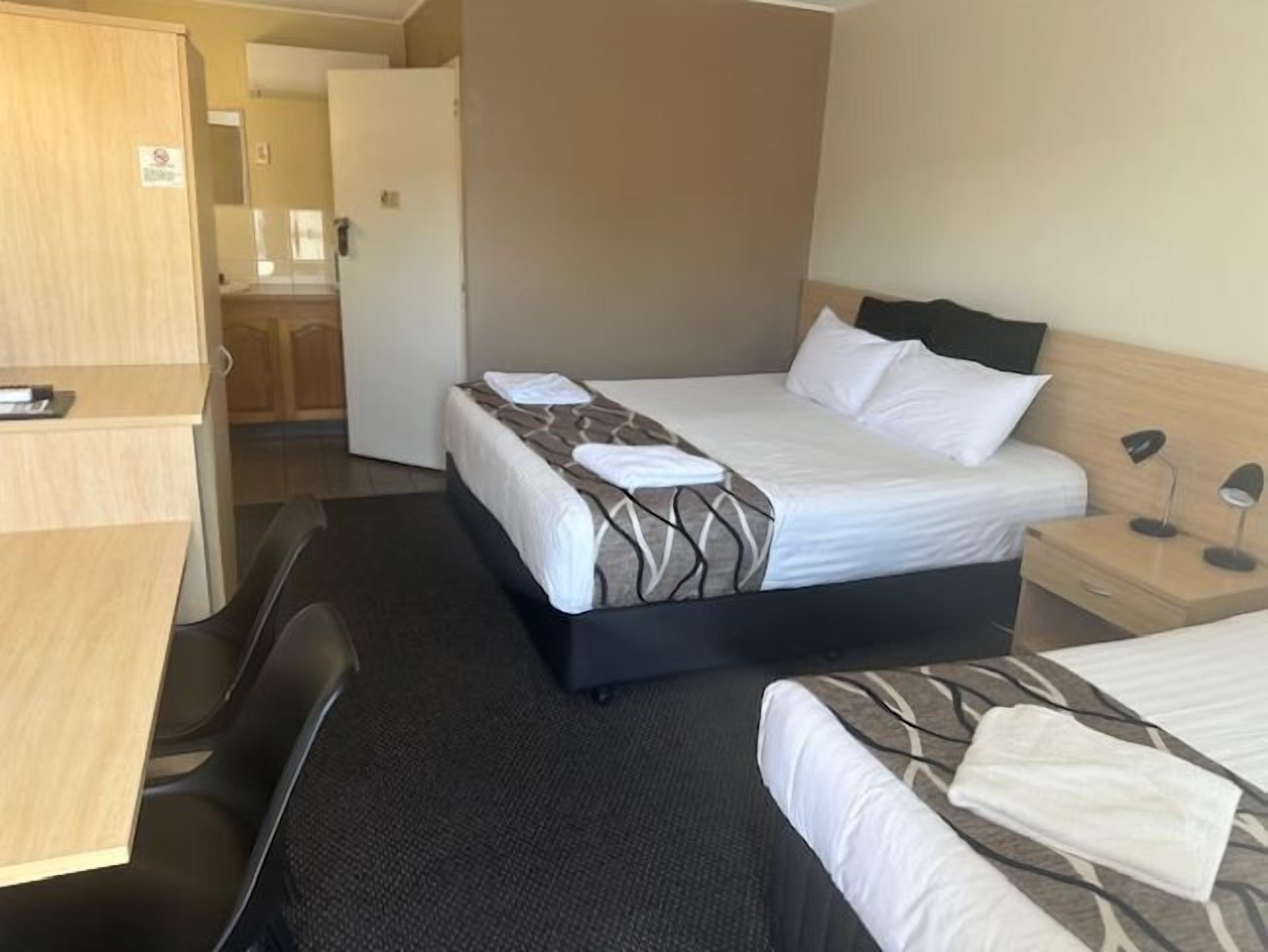 Una habitación de hotel con cama, escritorio, silla y armario.