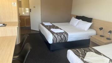 Una habitación de hotel con cama, escritorio, silla y armario.