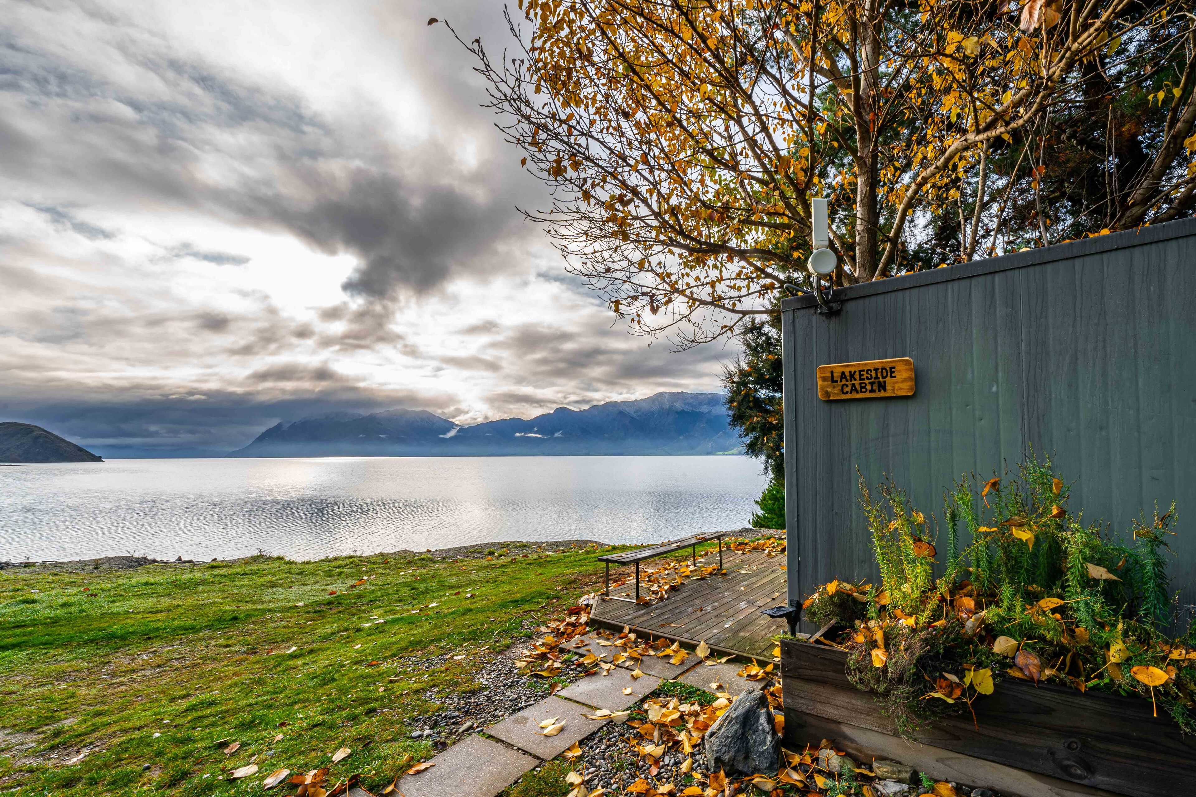 A cabin named "Lake Stede Cabin" with a view of a lake and mountains in the background.