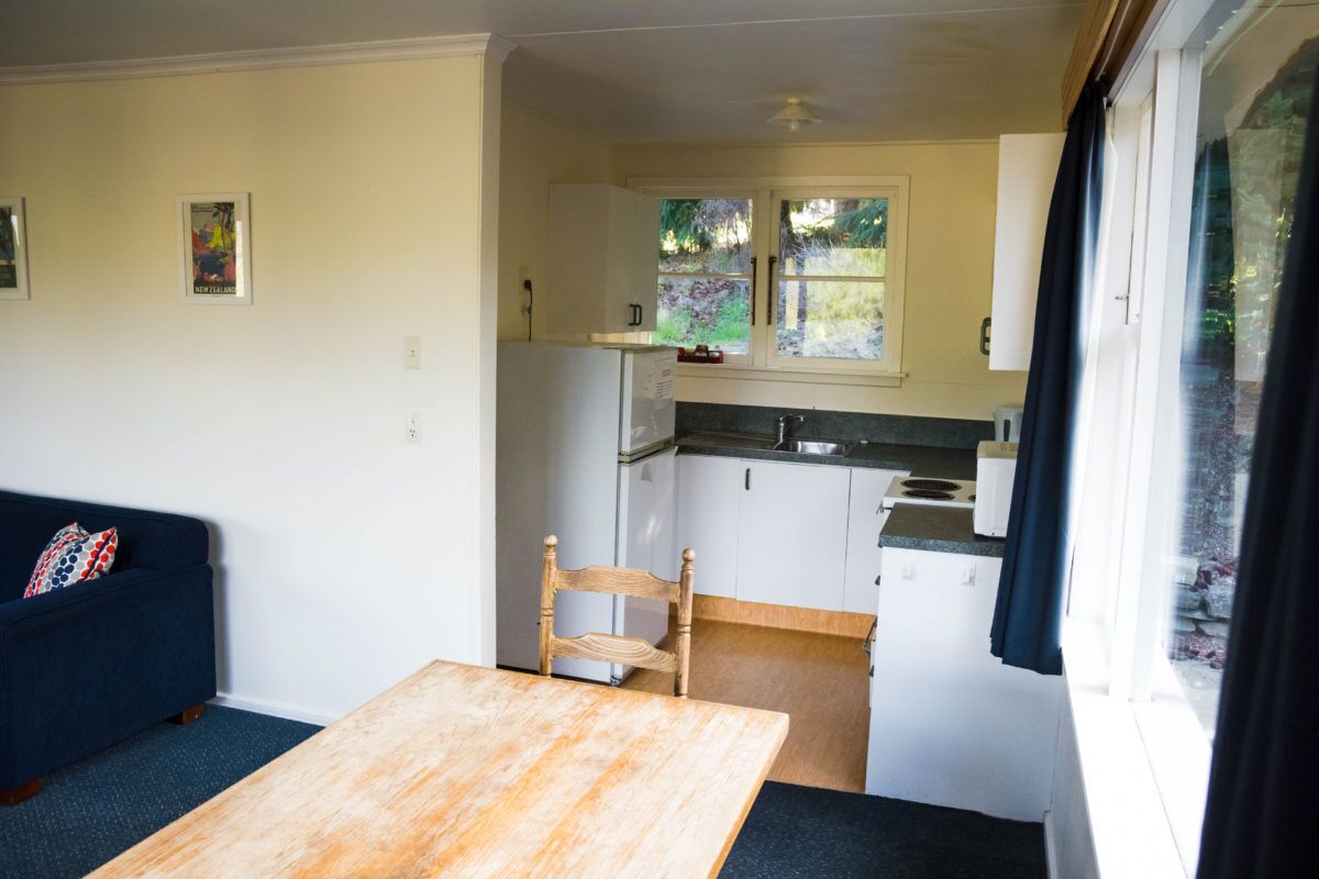 A compact living space with a kitchenette, a dining area with a table and chair, and a sofa.