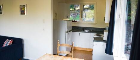 A compact living space with a kitchenette, a dining area with a table and chair, and a sofa.