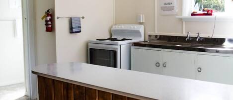 Una cocina con encimera de madera, armarios blancos, estufa y ventana con vista a follaje.