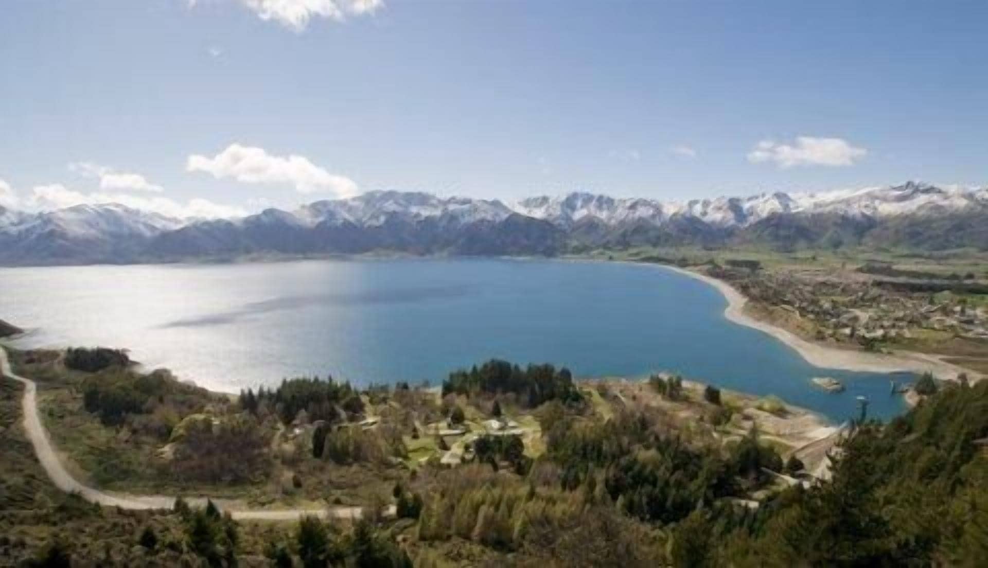 A lake surrounded by mountains and a small settlement with visible buildings and paths.