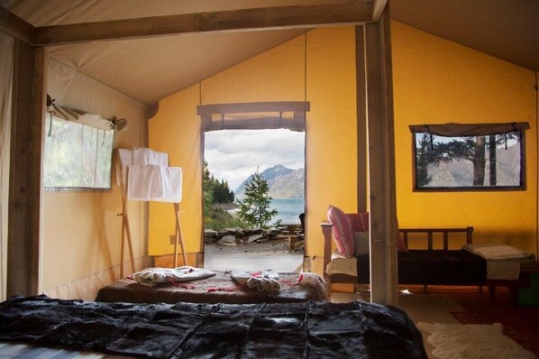 A cozy room with a bed, a chair, a small table, and a window offering a mountain view.