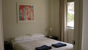 A neatly made bed with two pillows, a bedside lamp, and a painting on the wall. - Willow Dene (Bright)