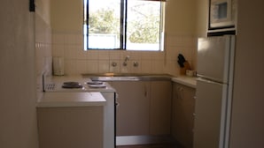 A compact kitchen with white cabinets, a built-in microwave, a sink, and a refrigerator. - Willow Dene (Bright)