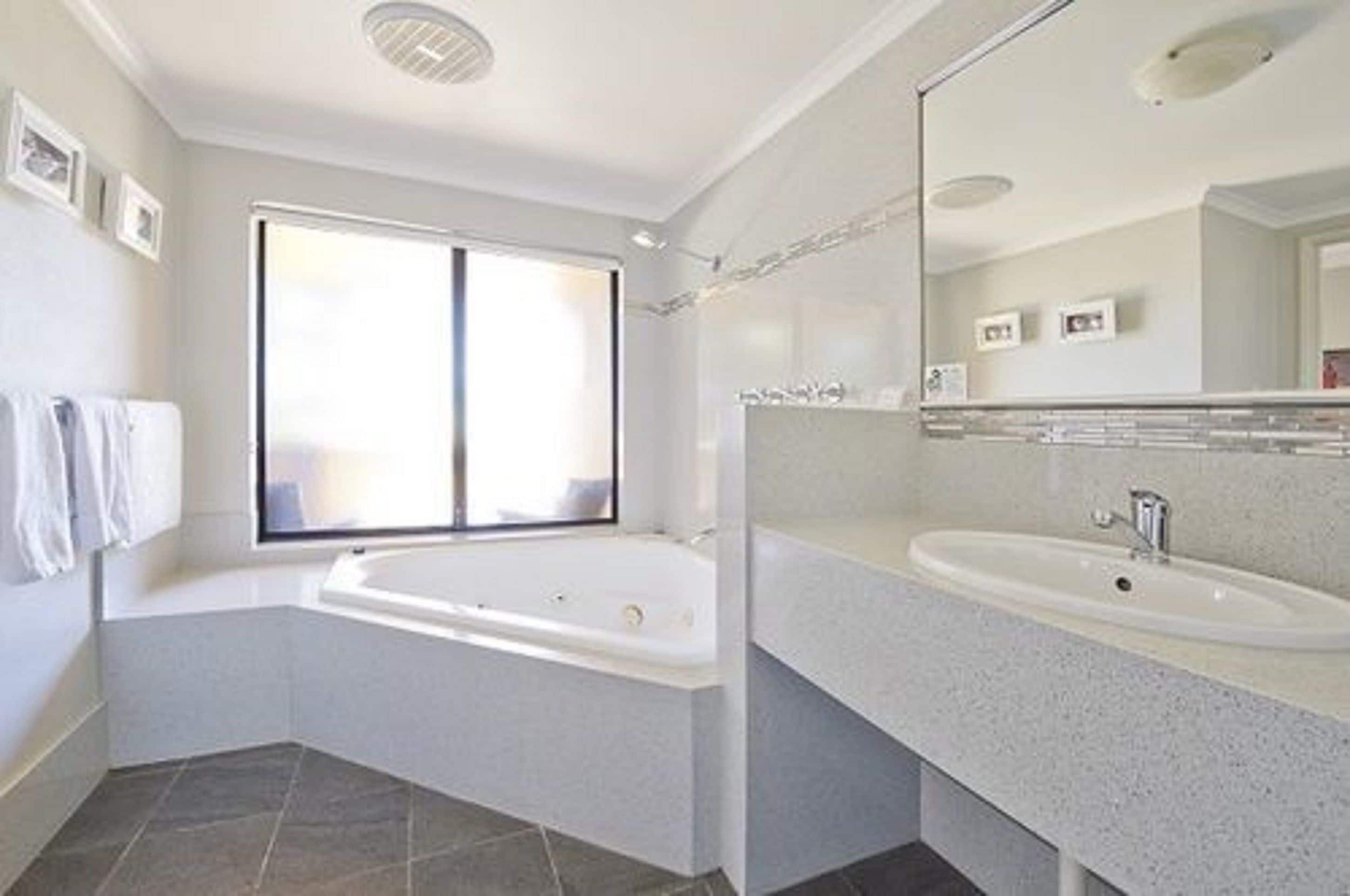 Un baño moderno con una bañera independiente, un espejo grande y un lavabo.