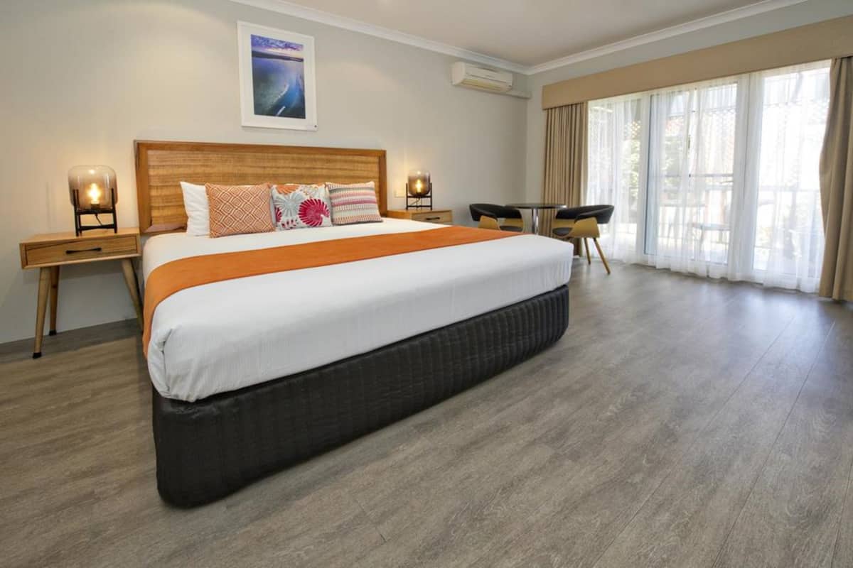 Ein Hotelzimmer mit einem großen Bett, zwei Nachttischen, einem Schreibtisch und einem Stuhl.